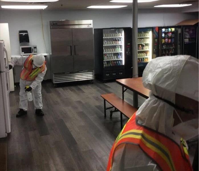 two PPE donned workers wiping down snack room