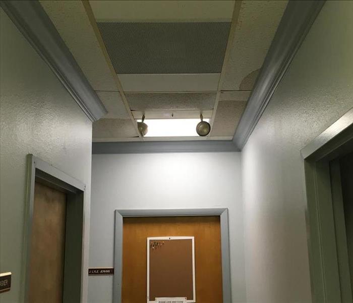 visible water stains on ceiling tiles, hallway of commercial building