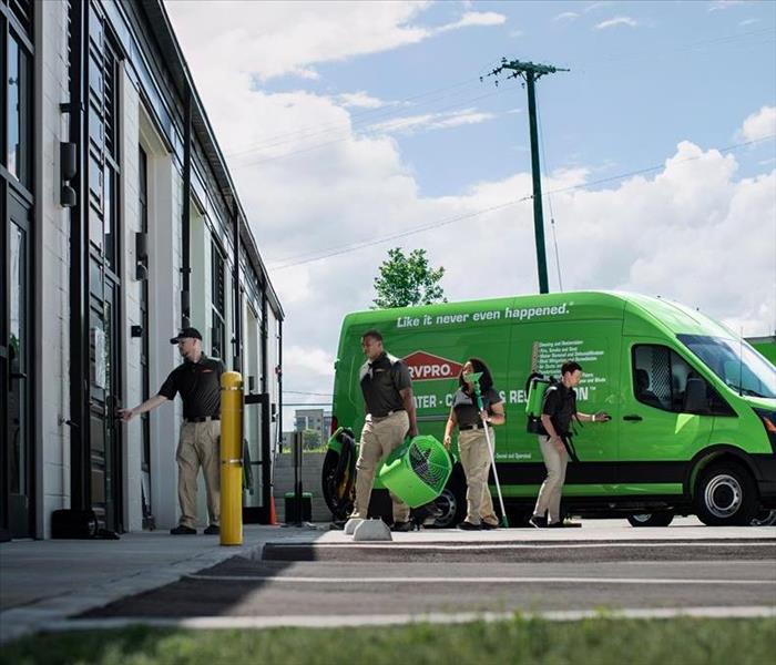 SERVPRO Employees moving equipment from a van into a building.
